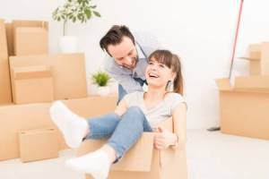 73650962-young-couple-people-have-fun-while-moving-to-a-new-apartment-boy-pushes-box-with-the-girl-happy-peop